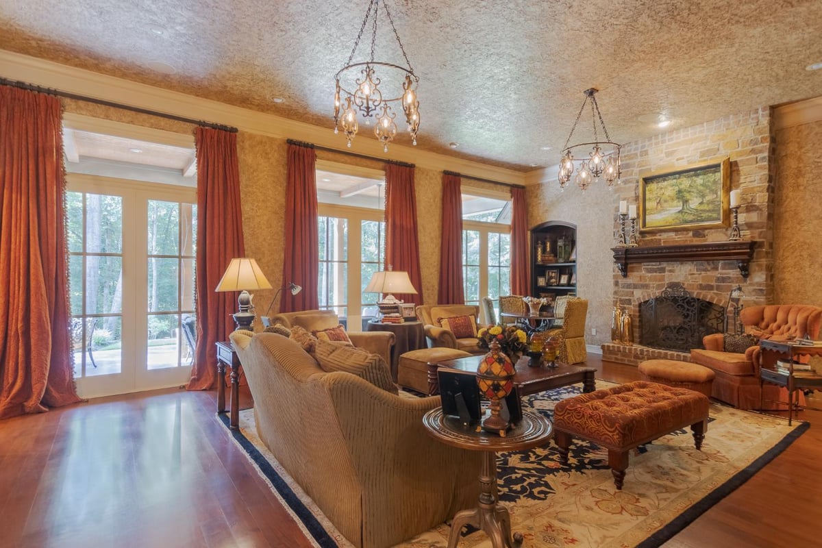 Elegant Country French custom home living room by Bort Design featuring a stone fireplace, hardwood floors, and soaring windows -optimized