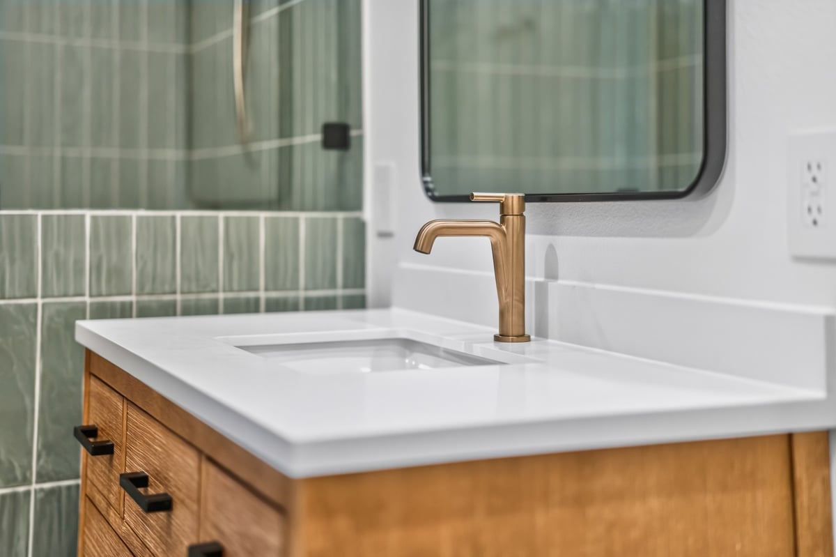 bathroom vanity with brass faucet and green tile shower in longview texas custom home