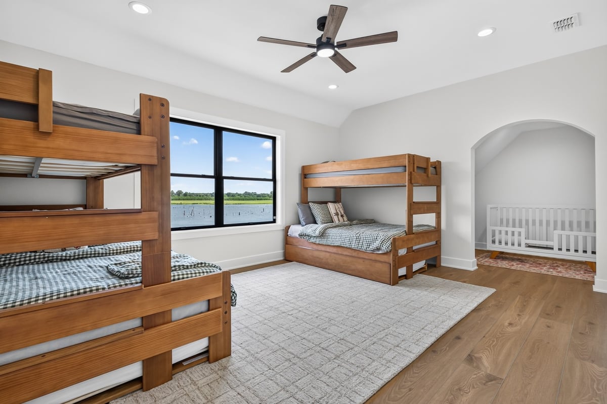 bunk room with wood beds and lake view window in longview texas custom home