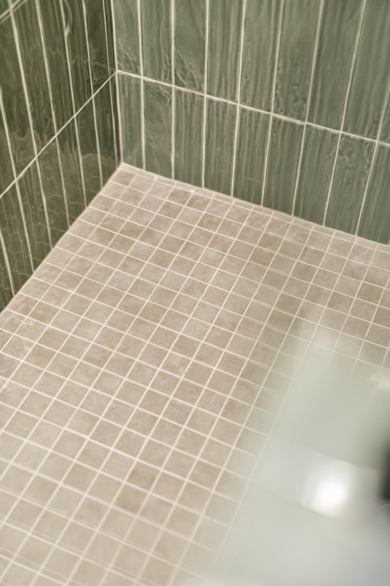 close up of green shower tile and mosaic floor in longview texas custom home