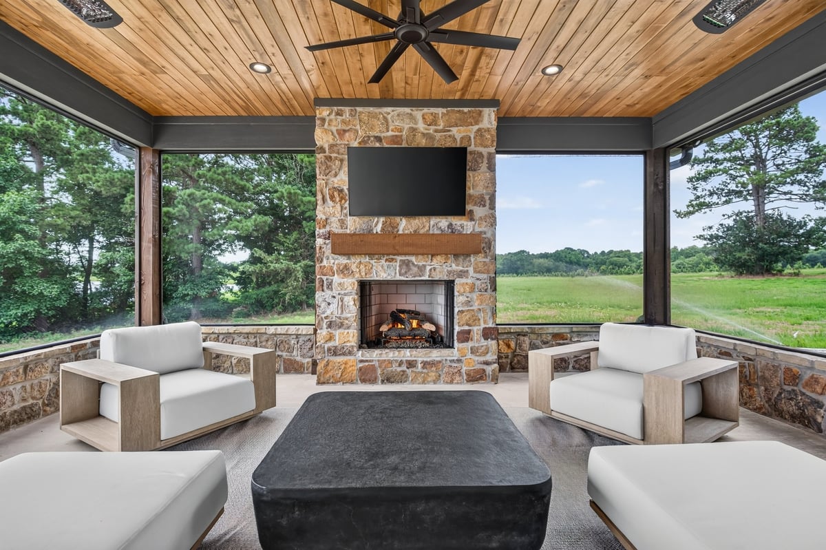 covered patio with stone fireplace and lounge seating in longview texas custom home