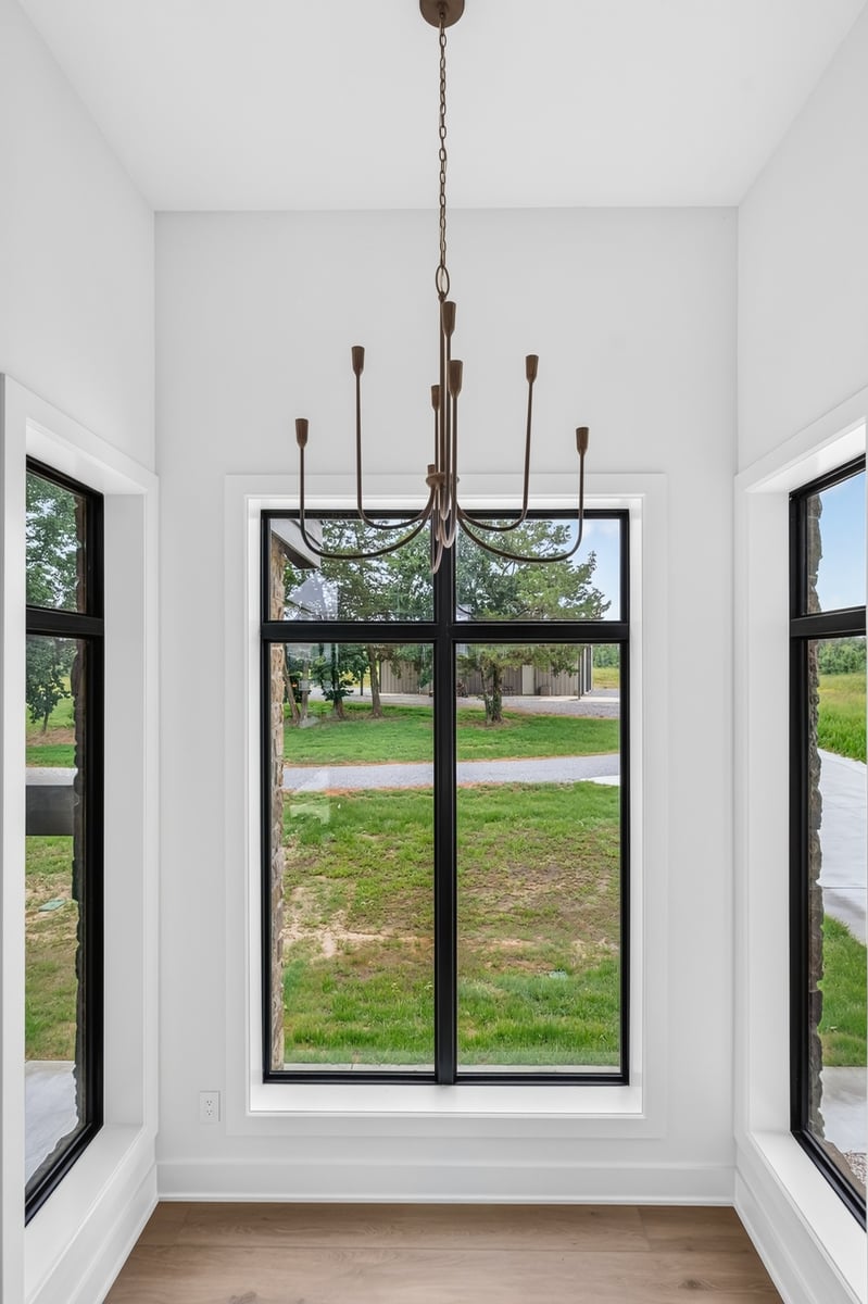 dining area with tall black framed windows and modern chandelier in longview texas custom home