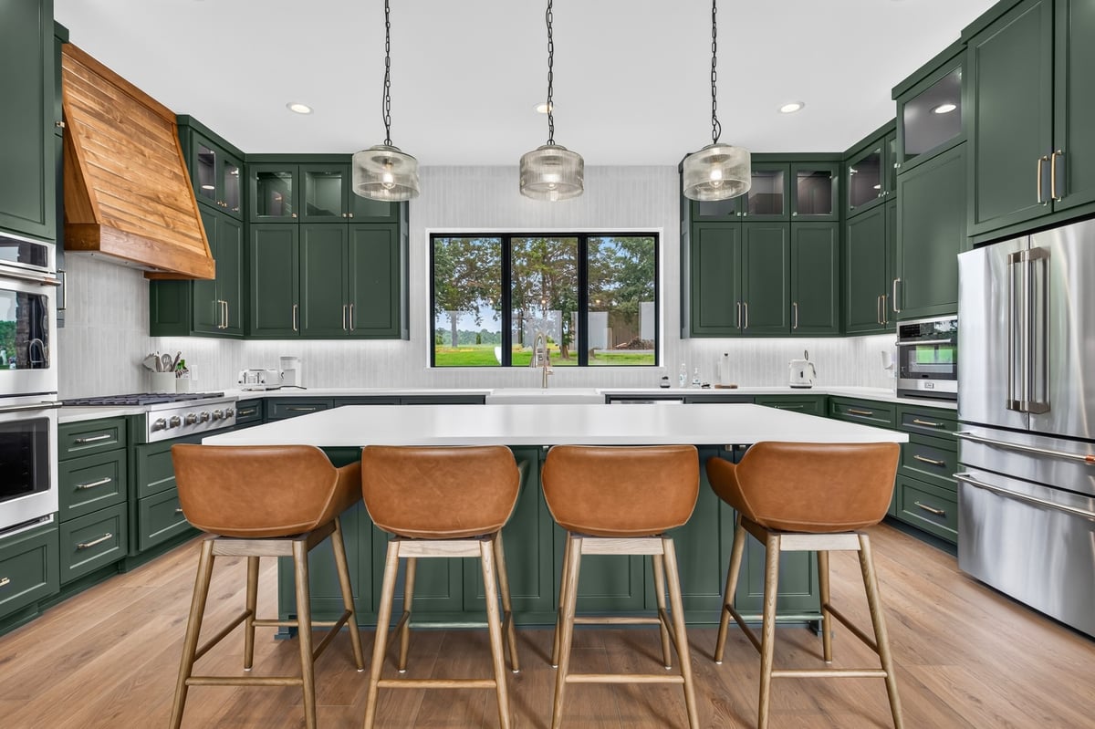 green custom kitchen with large island and leather stools in longview texas custom home