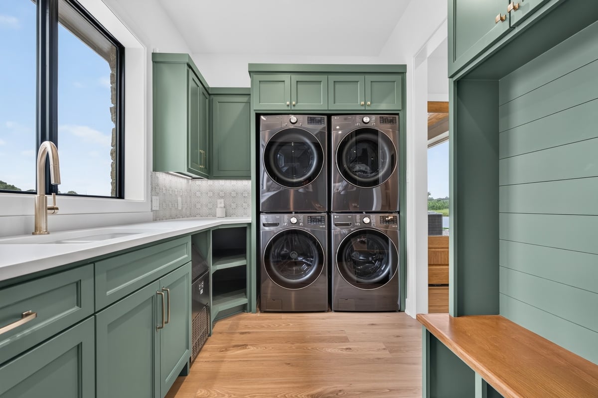 green custom laundry room with stacked washers and dryers in longview texas custom home