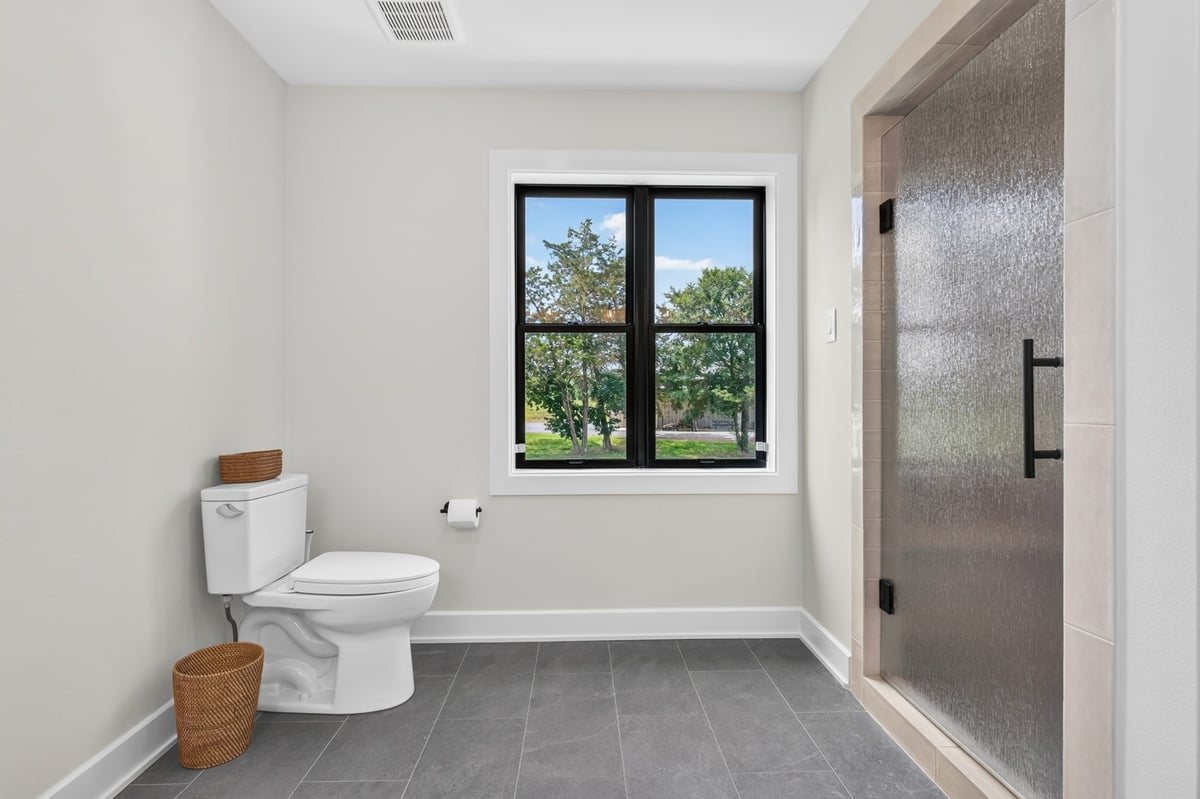 guest bathroom with toilet and textured glass shower door in longview texas custom home