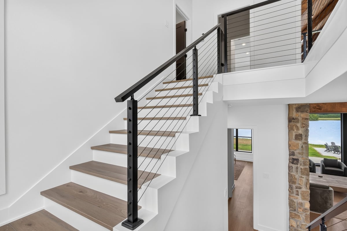 modern staircase with cable railing overlooking lake in longview texas custom home