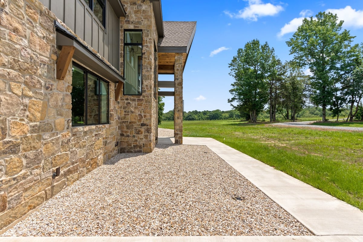 stone exterior side elevation with gravel landscaping in longview texas custom home