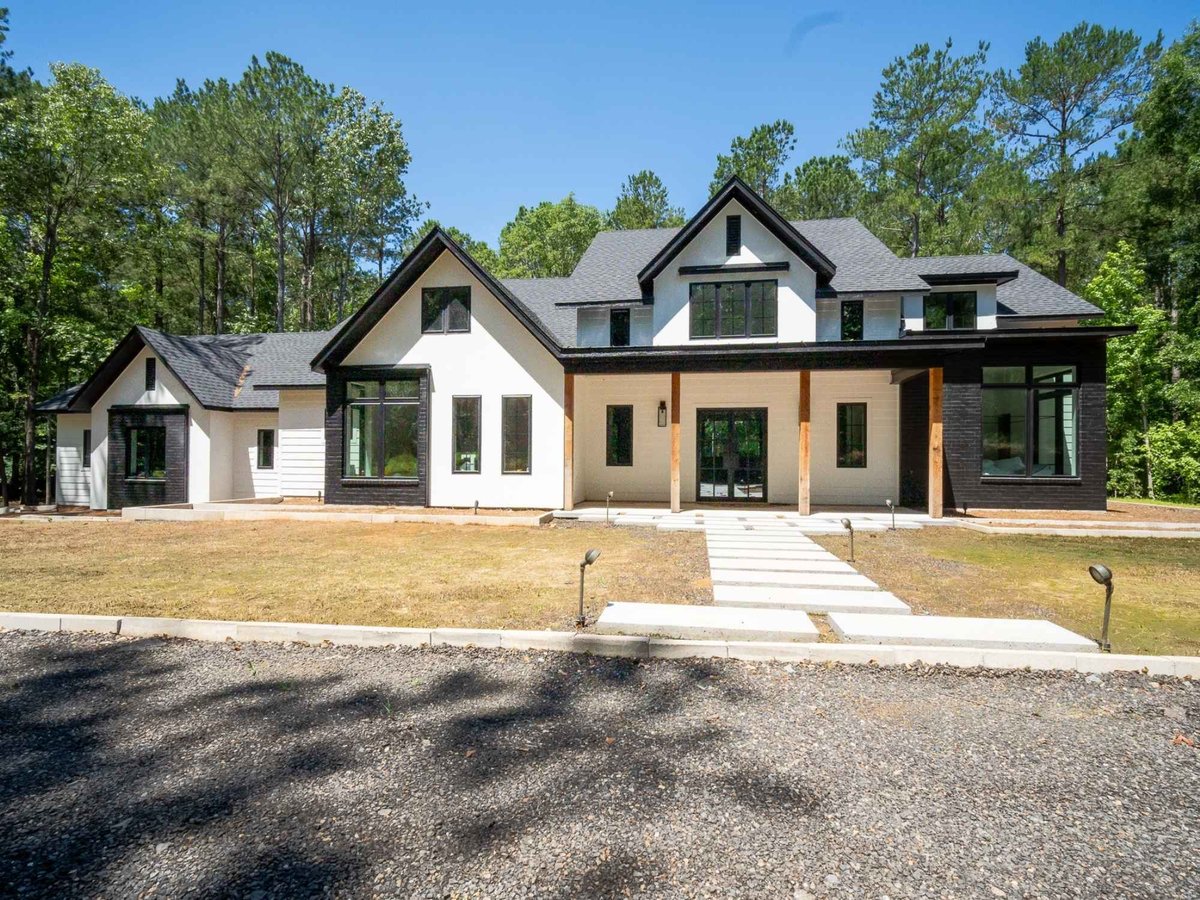 Photo of a modern custom home exterior with white siding, black accents, and covered porch in East Texas.