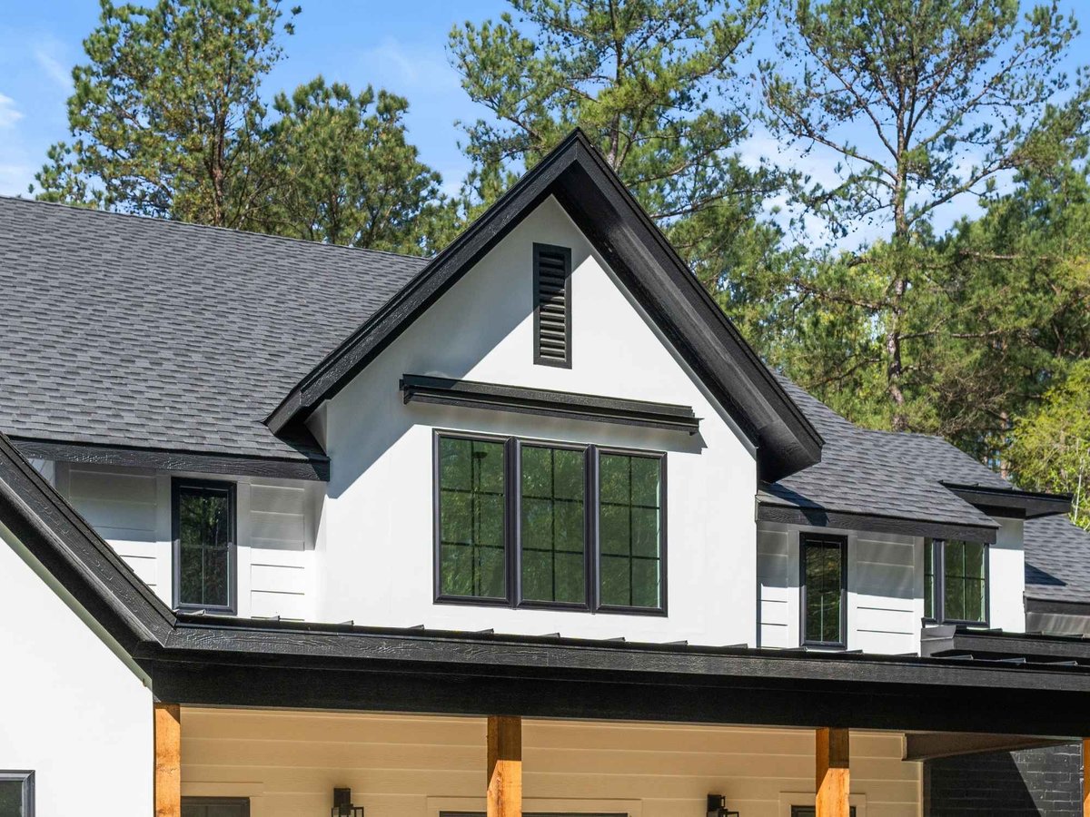 Photo of a modern white home exterior with black trim, gabled roof, and large windows in East Texas.