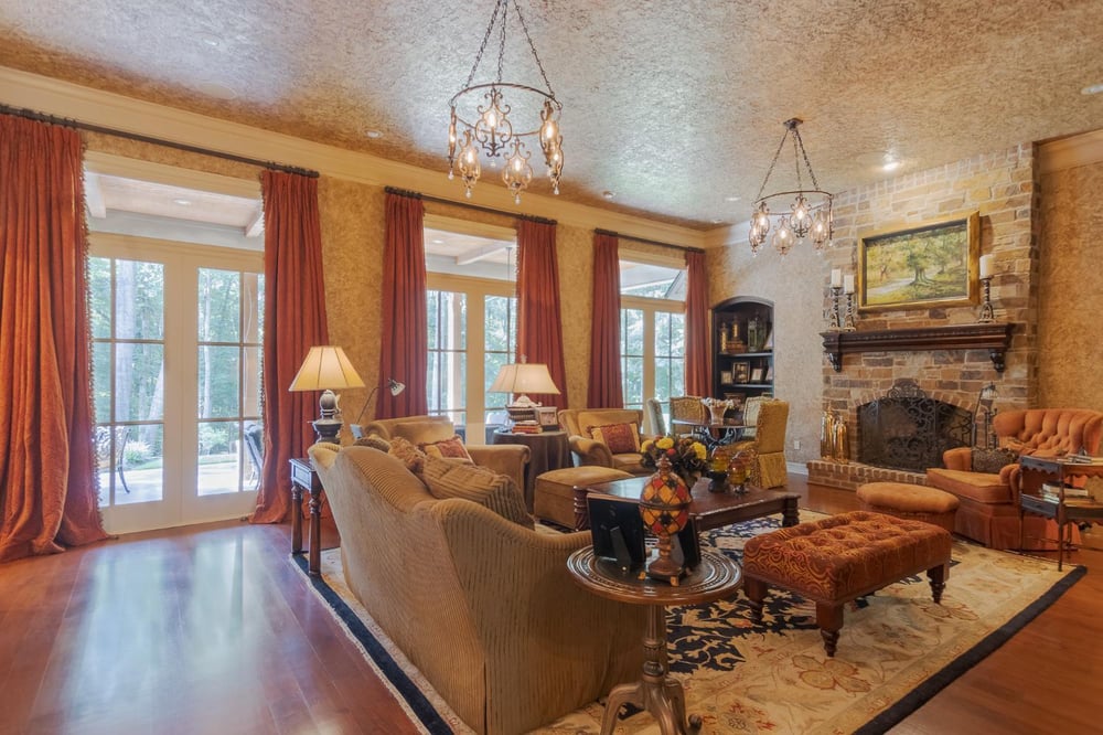 Elegant Country French custom home living room by Bort Design featuring a stone fireplace, hardwood floors, and soaring windows -optimized
