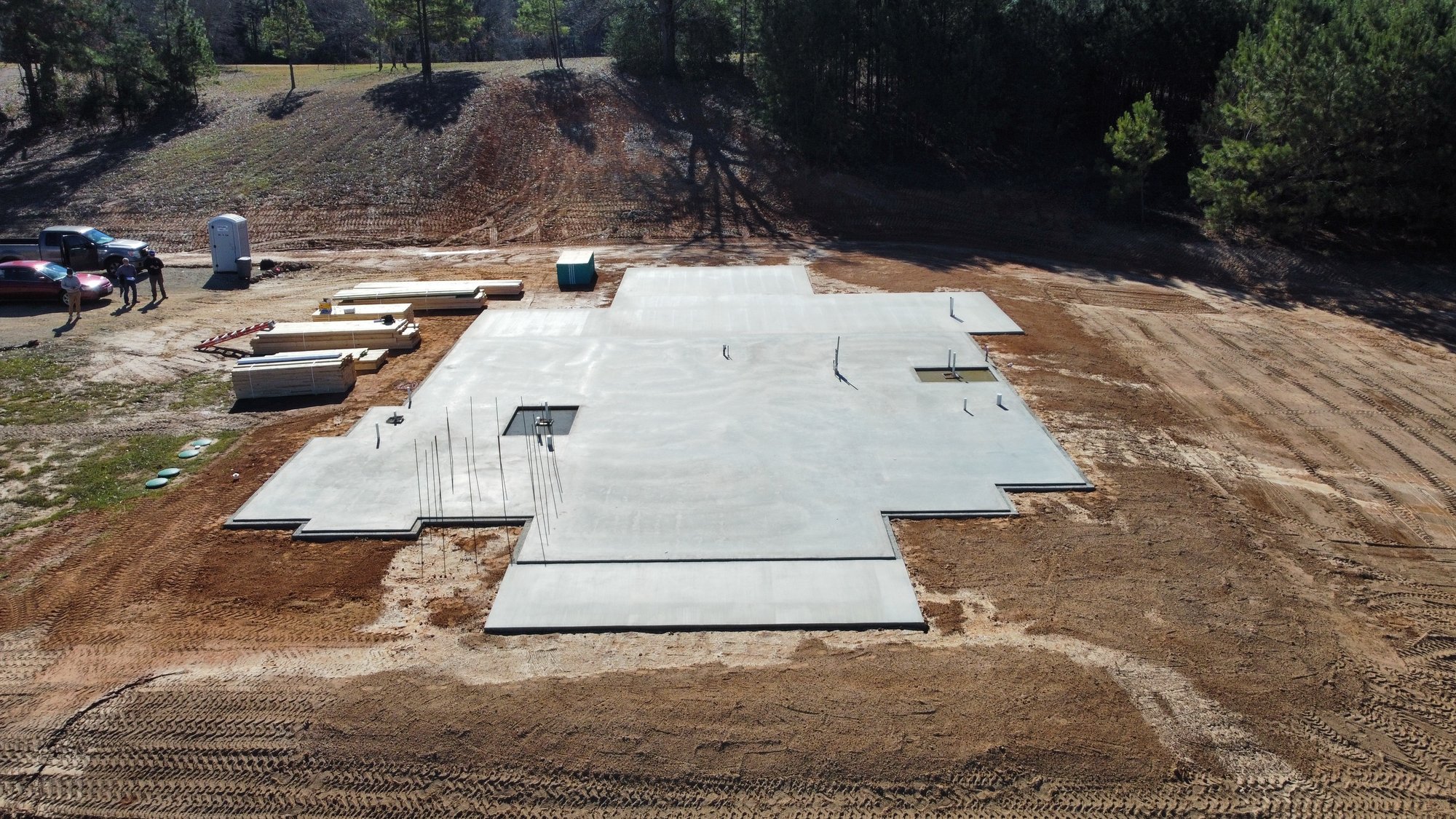 Aerial view of the concrete foundation for Bort Custom Homes’ custom home in Henderson, TX, with framing materials staged beside the slab.
