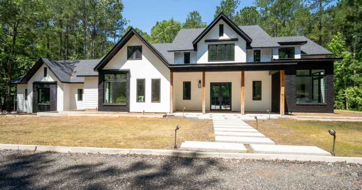 Photo of a modern custom home exterior with white siding, black accents, and covered porch in East Texas